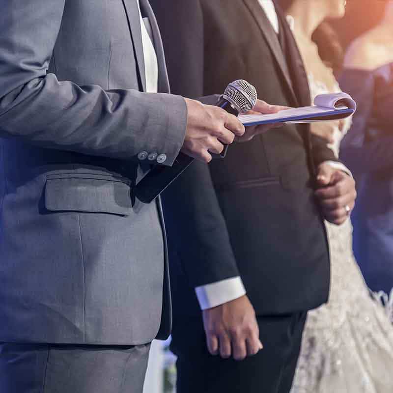 Homme en costume avec un micro et un carnet de notes durant un discours de mariage